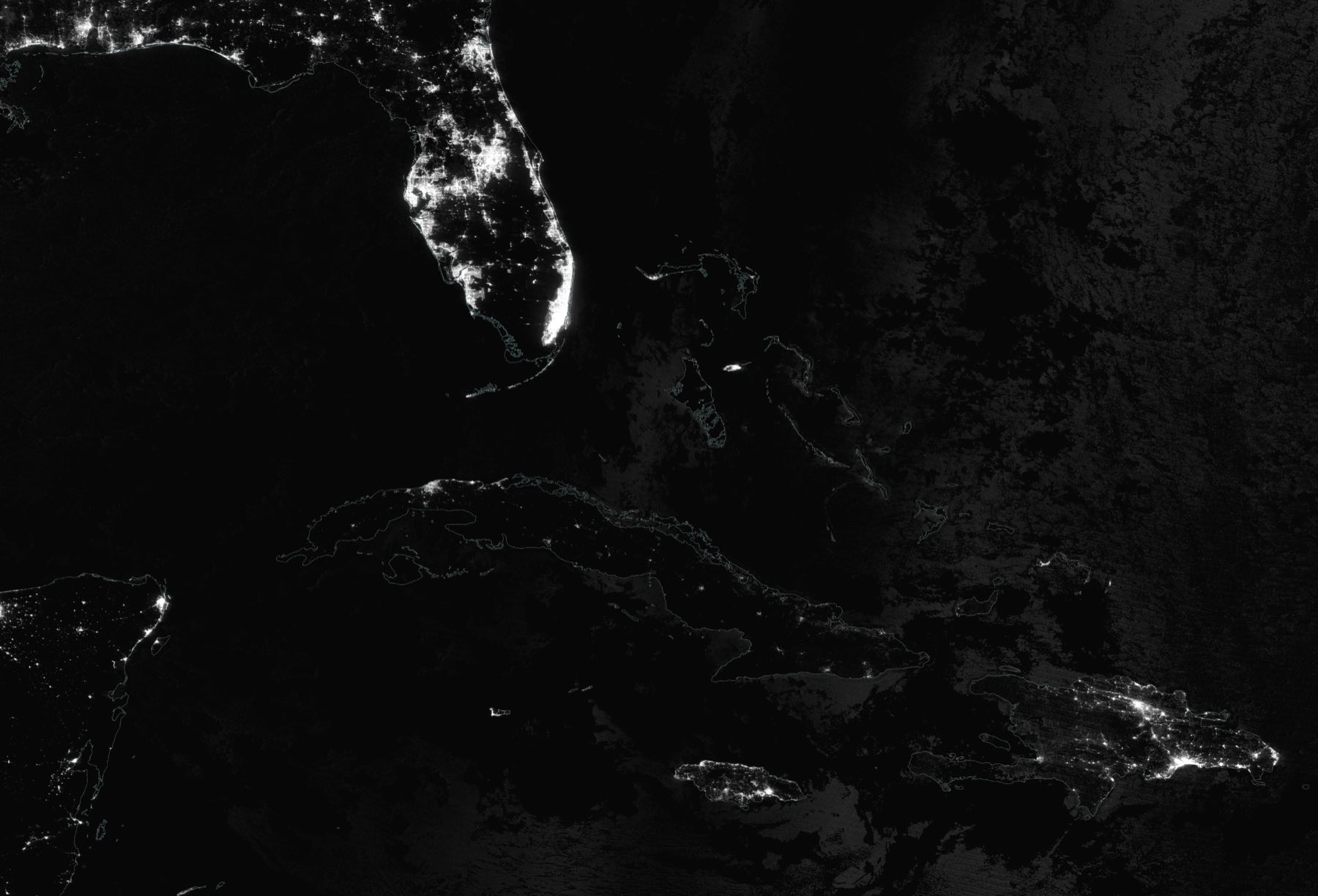 Immagine satellitare notturna: la Florida coperta di luci bianche, Cuba quasi interamente scura, novanta miglia più a sud.